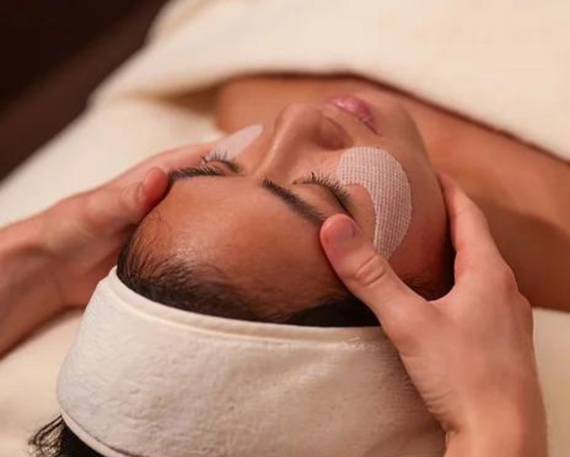 Person receiving a facial treatment with a white towel on their head.